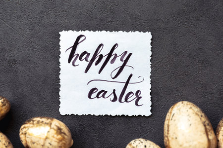 Happy Easter concept. Preparation for holiday. Golden Easter eggs Inscription HAPPY EASTER letters text on grunge scratched dark black shale background. Flat lay top view copy spaceの写真素材