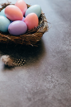 Happy Easter concept. Preparation for holiday. Colorful pastel decorated easter eggs in nest on grunge scratched dark black shale background. Simple minimalism copy spaceの写真素材