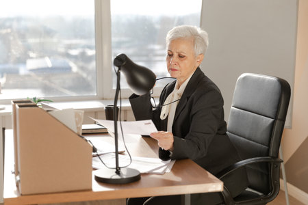 Confident stylish european middle aged senior woman reading financial report documentation statistics. Stylish older mature 60s gray haired lady businesswoman in office. Boss leader teacherの写真素材
