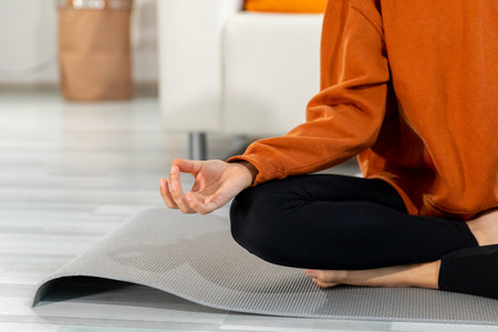 Yoga mindfulness meditation. Woman hands in chin mudra gesture. African girl practicing yoga at home. Woman sitting in lotus pose on yoga mat meditating relaxing indoor. Girl doing breathing practiceの写真素材