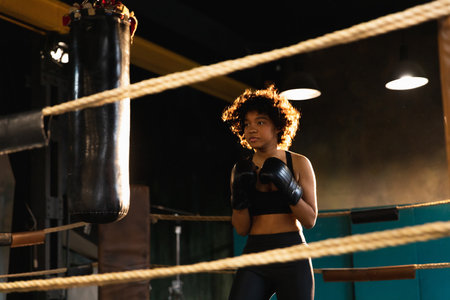 Women self defense girl power. African american woman fighter training punches on boxing ring. Healthy strong girl punching boxing bag. Training day in boxing gym. Strength fit body workout trainingの写真素材