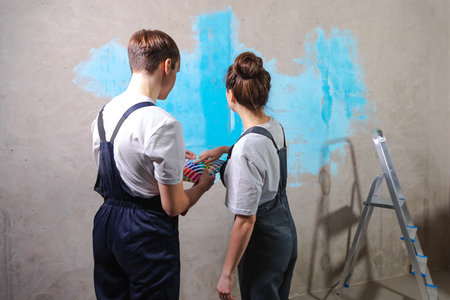 House decoration DIY renovation concept. Happy couple in empty room of new home planning design. Husband and wife holding swatch palette choosing colors for painting wall in new houseの写真素材