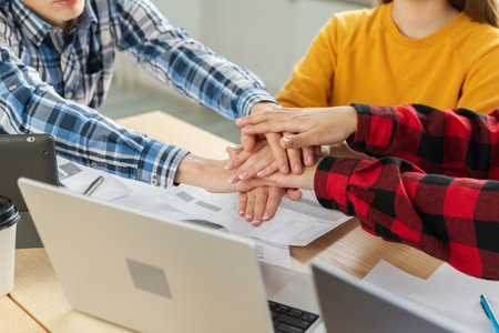 Stack of hands. Business startup teamwork unity concept. Diverse team putting their hands together top view. Young people group business colleagues sitting in office, work process success of companyの写真素材