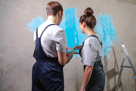 House decoration DIY renovation concept. Happy couple in empty room of new home planning design. Husband and wife holding swatch palette choosing colors for painting wall in new houseの写真素材
