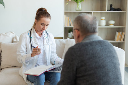 Female doctor examining older senior man in doctor office or at home. Old man patient and doctor have consultation in hospital room. Medicine healthcare medical checkup. Visit to doctorの写真素材