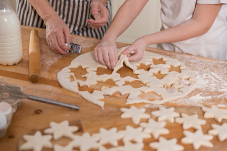 Family in kitchen. Grandmother granddaughter child hands cutting cookies of dough on kitchen table...
