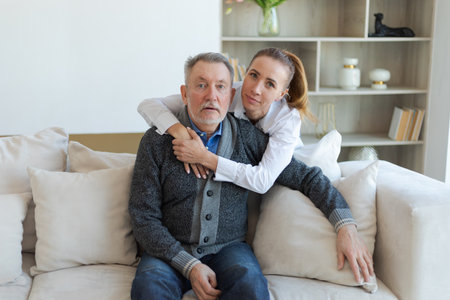 Happy family. Caring grown up daughter hugging loving older man father. Young woman embracing dad...