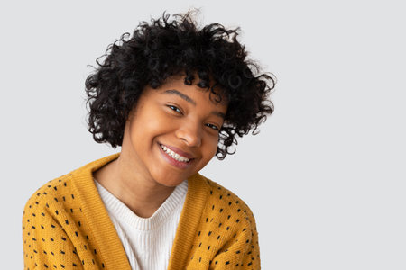 Beautiful african american girl with afro hairstyle smiling isolated on white background with copy...