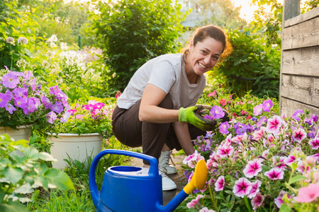 Gardening and agriculture concept. Young woman farm worker gardening flowers in garden. Gardener...