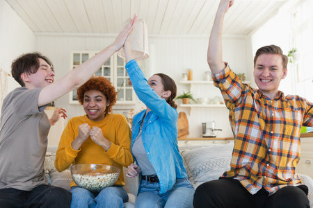 Group of friends watching sport match soccer football game on tv. Happy football fans celebrating...