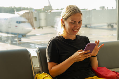 Airport terminal. Woman waiting for flight using smartphone. Girl with cell phone in airport surfing...