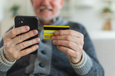 Senior man shopping online holding smartphone paying with credit card. Old grandfather buying on Internet enter credit card details. Online shopping delivery service Older generation modern tech usageの写真素材