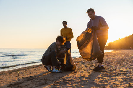 Earth day. Volunteers activists collects garbage cleaning of beach coastal zone. Woman and mans puts...