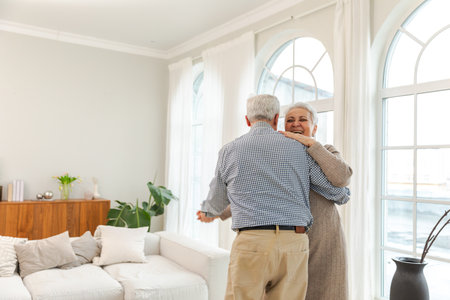 Keep moving. Romantic senior mature couple dancing to music together at home. Happy smiling family retired man woman husband wife having fun enjoying time together. Family moment love careの写真素材