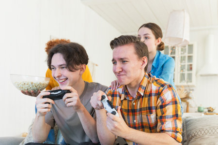 Home party. Cheerful group of friends playing video games at home. Happy diverse group buddies...