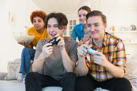 Home party. Cheerful group of friends playing video games at home. Happy diverse group buddies...