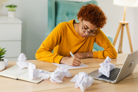 Serious African woman with crumpled paper having problem writing by hand document studying learning...