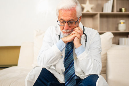 Sad tired mature senior male doctor in medical uniform in hospital or doctor office. Unhappy General Practitioner GP therapist professional healthcare expert in clinic. Healthcare conceptの写真素材