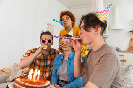 Make a wish. Woman wearing party cap blowing out burning candles on birthday cake. Happy Birthday...