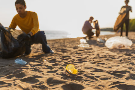 Earth day. Volunteers activists collects garbage cleaning of beach coastal zone. Woman mans with trash in garbage bag on ocean shore. Environmental conservation coastal zone cleaning. Blurred imageの写真素材