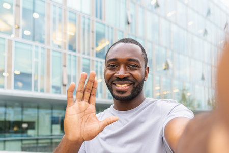 African American man with smartphone having video call on street in city. Guy blogger streaming chatting in social network. Man having virtual meeting vlog online chat outdoor Selfie webcamera viewの写真素材