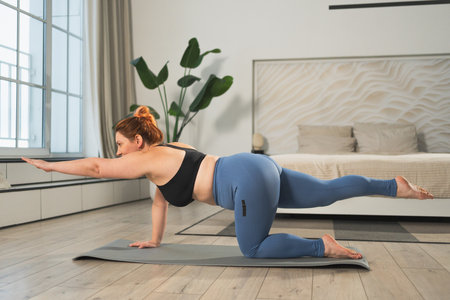 Yoga fitness workout training. Woman practicing yoga at home. Plus size female doing sports exercise...