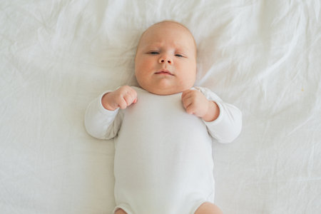 Happy baby. Cute little newborn girl with smiling face lying on bed in bedroom. Infant baby resting...