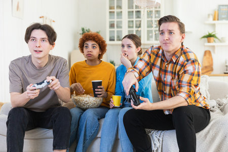 Home party. Cheerful group of friends playing video games at home. Happy diverse group buddies...
