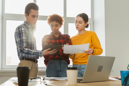 Teamwork brainstorm young professional team concept. Happy multiracial coworkers cooperating working together at office meeting. Diverse colleagues discussing project ideas editing documentationの写真素材