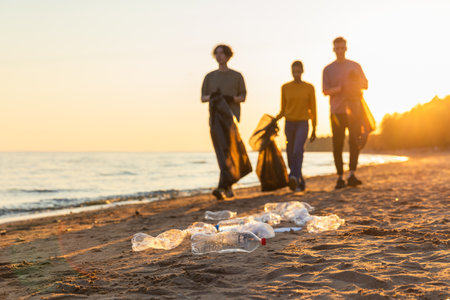 Earth day. Volunteers activists team collects garbage cleaning of beach coastal zone. Woman mans...