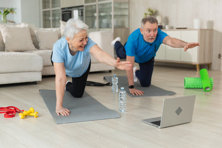 Fitness workout training. Senior adult mature healthy fit couple doing sports exercise on yoga mat on floor at home. Mid age old husband wife have training workout. Health care healthy lifestyleの写真素材