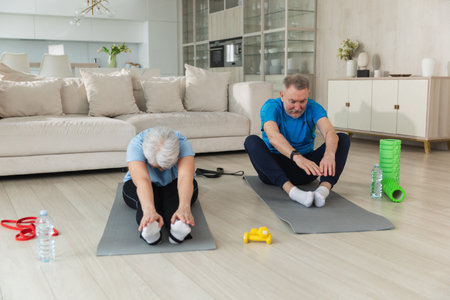 Fitness workout training. Senior adult mature healthy fit couple doing sports exercise on yoga mat on floor at home. Mid age old husband wife have training workout. Health care healthy lifestyleの写真素材