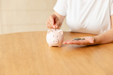 Saving money investment for future. Senior adult mature woman hands putting money coin in piggy bank. Old grandmother counting saving money planning retirement budget. Investment banking conceptの写真素材
