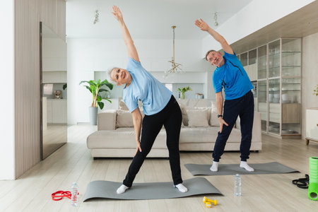 Fitness training. Senior mature healthy fit couple doing sports exercise at home. Mid age husband wife have training workout. Health care healthy lifestyle. Workout rehabilitation for old man womanの写真素材
