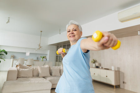 Fitness workout training. Senior woman picking up dumbbells. Old adult mature healthy lady doing sports exercise at home. Grandmother have workout rehabilitation. Health care healthy lifestyleの写真素材