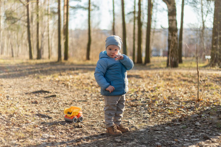 Happy baby child outdoor. Little toddler boy with toy car having fun on walk in park. Baby son smiling playing outdoor. Little child resting walking in nature. Little toddler child having fun on walkの写真素材