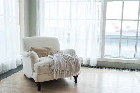Stylish loft interior. Spacious design apartment with light walls large windows white armchair. Clean modern decoration with elegant furniture in minimalist Scandinavian styleの写真素材