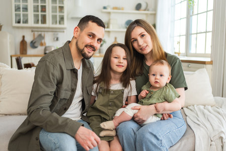 Happy family at home. Mother father two children daughters relaxing on sofa indoor. Mom dad parents...