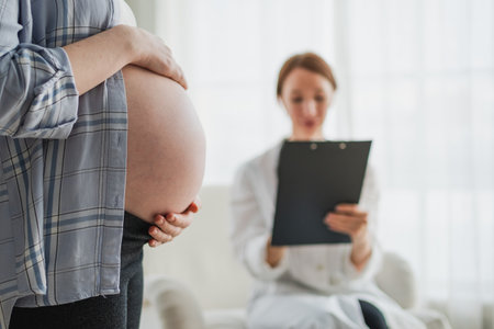 Pregnant woman hands touching big belly in doctor office. Female doctor examining pregnant woman....