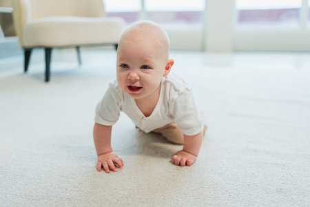 Happy baby. Cute little newborn girl with smiling face crawling on floor in bedroom. Infant baby resting playing in living room indoor at home. Motherhood happy child childcare conceptの写真素材