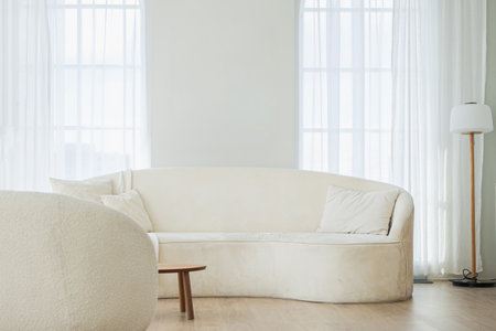 Stylish loft bedroom interior. Spacious design apartment with light walls large windows white couch sofa and armchair. Clean modern decoration with elegant furniture in minimalist Scandinavian styleの写真素材