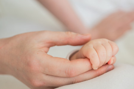 Happy family. Tiny newborn infant baby little hand on mother hand palm. Newborn baby holding parent finger after birth. Mom baby at home. Support protection of new life. Handle with careの写真素材