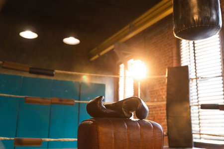Boxing gloves lying down on boxing ring in empty gym. Equipment for fight training competition black protective boxing gloves ready for fighter winner on ring. Strength fit body workout trainingの写真素材