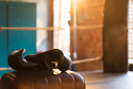 Boxing gloves lying down on boxing ring in empty gym. Equipment for fight training competition black protective boxing gloves ready for fighter winner on ring. Strength fit body workout trainingの写真素材