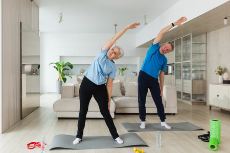 Fitness training. Senior mature healthy fit couple doing sports exercise at home. Mid age husband wife have training workout. Health care healthy lifestyle. Workout rehabilitation for old man womanの写真素材