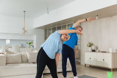 Fitness training. Senior mature healthy fit couple doing sports exercise at home. Mid age husband wife have training workout. Health care healthy lifestyle. Workout rehabilitation for old man womanの写真素材