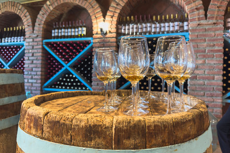 Many glasses of white wine on wooden barrel. Wine tasting event. Wine cellar with wine barrels. French wooden barrels. Wine shop wine bar winery or wine tasting conceptの写真素材