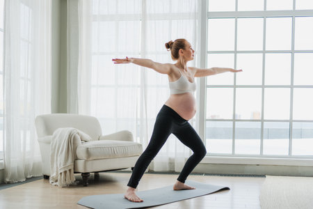 Pregnancy yoga fitness workout training. Pregnant woman practicing yoga at home. Pregnant girl doing sports exercise on yoga mat indoor. Woman with big belly have fitness training practicing asanaの写真素材