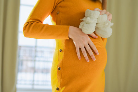 Pregnancy motherhood people expectation future. Big belly of pregnant woman, newborn baby booties in hands close up. Mom enjoying pregnancy relaxing at home. Maternity tenderness parenthood new lifeの写真素材