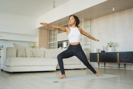 Yoga fitness workout training. Healthy African girl practicing yoga at home. Woman training doing sports exercise on yoga mat indoor. Girl have training workout for weight loss.の写真素材